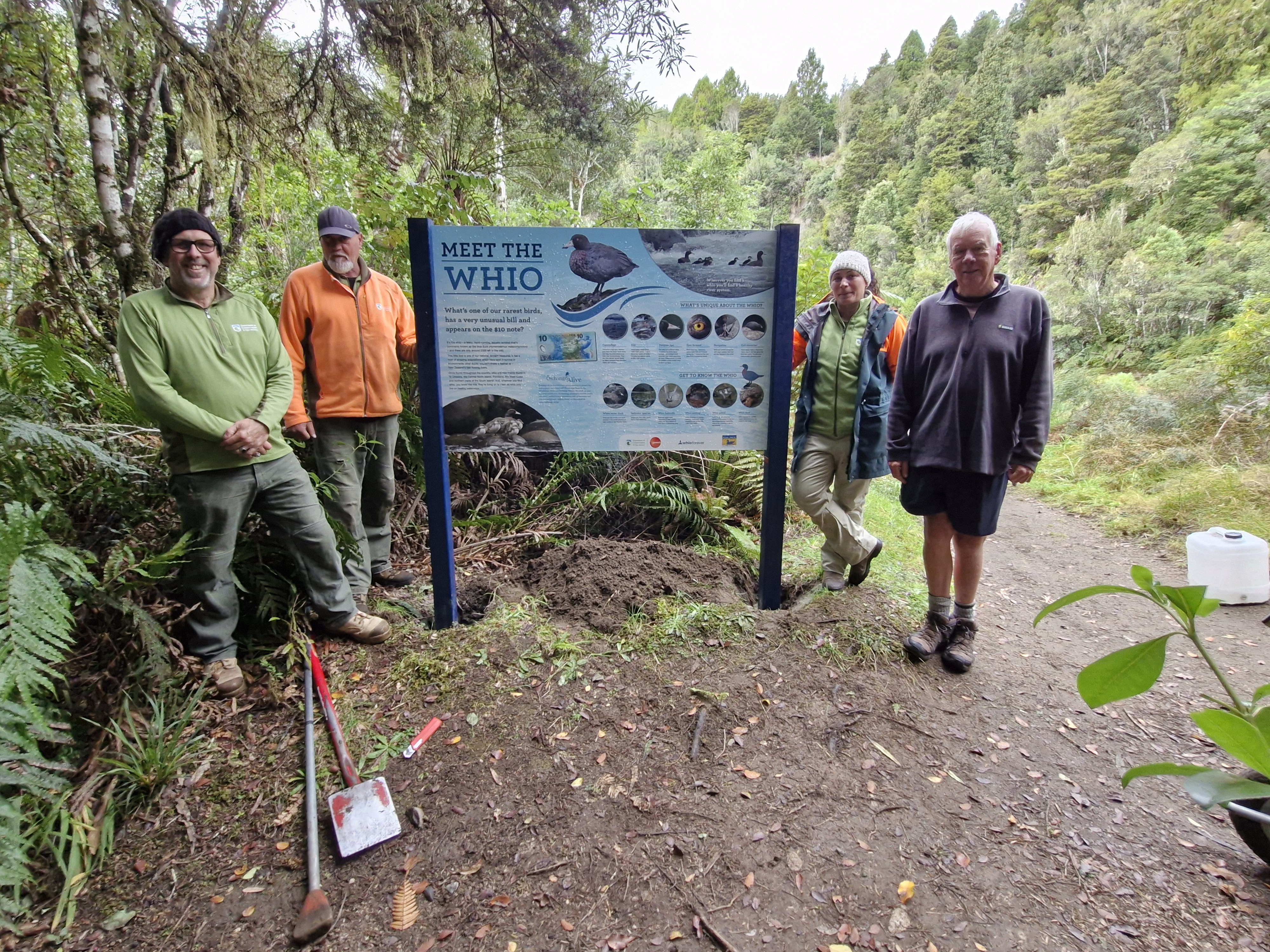 Owhango Alive volunteers standing beside the newly replaced Whio information panel at the Swimming Hole in Ohinetonga Scenic Reserve.